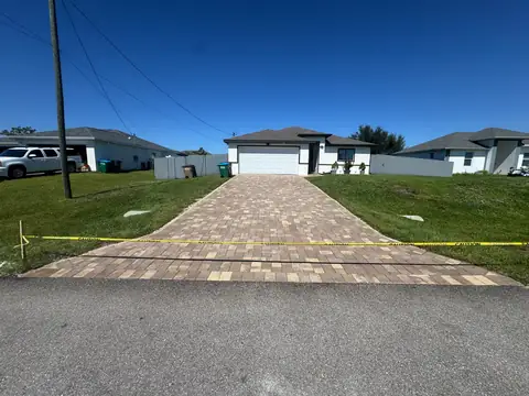 Light-colored paver driveway taped off after sealing