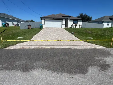 Paver driveway with caution tape across the front while the sealer cures