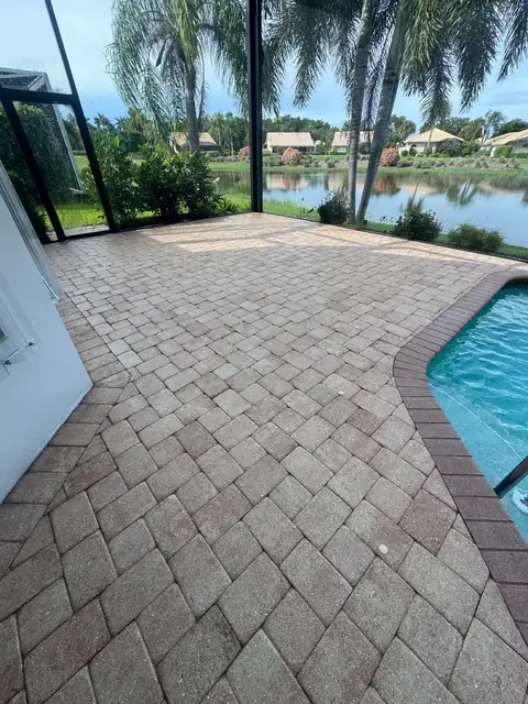 The same paver pool deck cleaned, beside the pool with a lake beyond