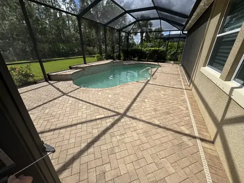 The same brick paver pool deck cleaned, inside a screen enclosure